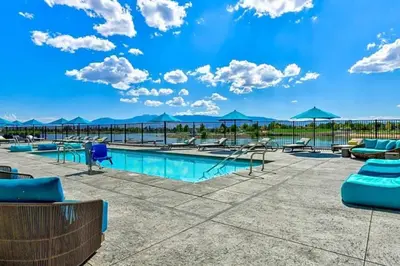 a pool with chairs and umbrellas on a patio at Chic Apt w Jacuzzi, Pool, BBQ, & Mountain Views in Sparks