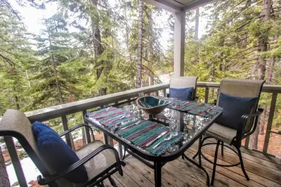 a table and chairs on a deck with a view at Woodsy retreat near Northstar & lake in Kings Beach