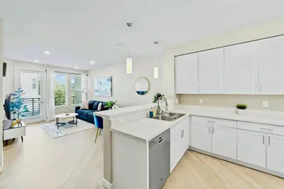 a kitchen with white cabinets and a living room at Chic Apt with Jacuzzi, Pool Nr Casino & Shopping in Sparks