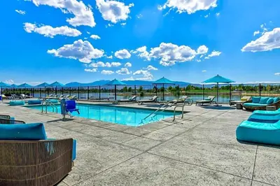 a pool with chairs and umbrellas on a patio at Chic Apt with Jacuzzi, Pool Nr Casino & Shopping in Sparks
