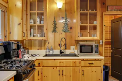 a kitchen with wooden cabinets and a sink and a stove at 3 Mi to Big Trees State Park Cabin with Scenic Deck in Arnold
