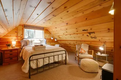 a bedroom with a bed in a log cabin at 3 Mi to Big Trees State Park Cabin with Scenic Deck in Arnold