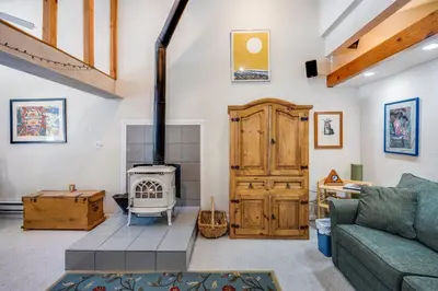a living room with a couch and a wood stove at Sunny Studio Ski Loft - Creekside #103 in Bear Valley