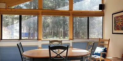 a dining room with a table and chairs and windows at Sunny Studio Ski Loft - Creekside #103 in Bear Valley