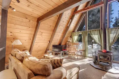 a living room of a log cabin with a large window at Popular A-frame Cabin With Deck & Views - Vh 216 in Bear Valley