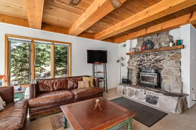 a living room with a couch and a stone fireplace at Mountain Getaway with Granny Unit, Dogs Ok #47 in Bear Valley