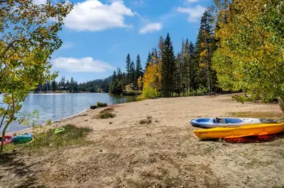 two kayaks on a sandy beach next to a lake at Modern Condo - Great Location! in Bear Valley