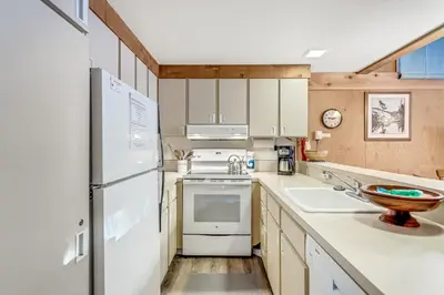 a kitchen with white appliances and wooden cabinets at Modern & Sleek Condo - Creekside #110 in Bear Valley