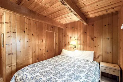 a bedroom with a bed in a wooden wall at Lancaster Cabin in Bass Lake