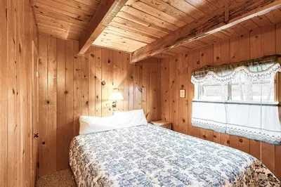 a bedroom with a bed in a wooden room at Lancaster Cabin in Bass Lake