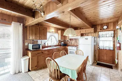 a kitchen with a table and a white refrigerator at Lancaster Cabin in Bass Lake