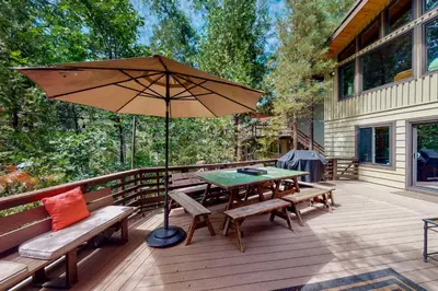 a patio with a table and benches and an umbrella at Twets Lakefront in Bass Lake