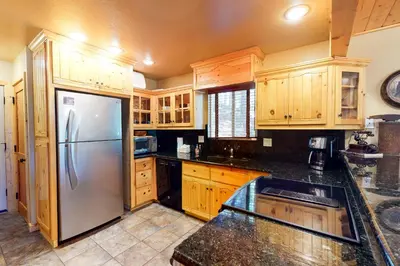 a kitchen with wooden cabinets and a stainless steel refrigerator at Yosemite Silvertip Lodge in Fish Camp
