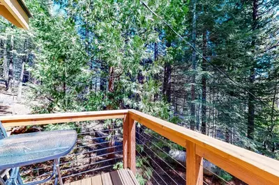 a balcony with a chair and trees in the background at Yosemite Silvertip Lodge in Fish Camp