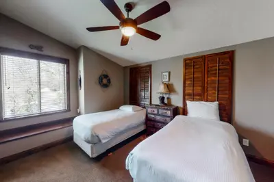a bedroom with two beds and a ceiling fan at Brickers Lakefront in Bass Lake