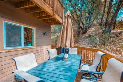 a table and chairs on a porch with a umbrella at Robinson Shoreline House in Bass Lake