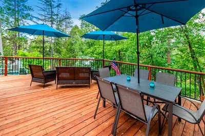 a wooden deck with a table and chairs with umbrellas at Brier Escape in Bass Lake