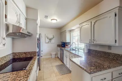 a kitchen with white cabinets and marble counter tops at Putney Place in North Fork