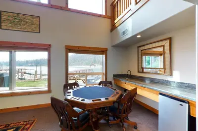 a dining room with a table and chairs and windows at Humphreys Lakefront in Bass Lake