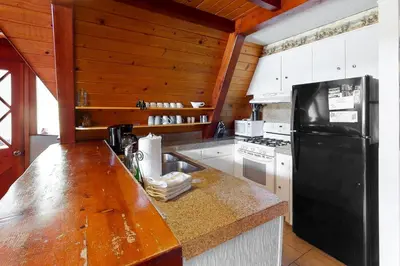 a kitchen with a black refrigerator and white cabinets at Alford Family Lodge in Bass Lake