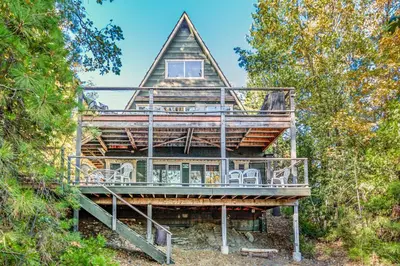 a large wooden house with a deck and chairs at Alford Family Lodge in Bass Lake