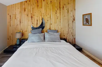 a bed in a room with a wooden wall at Todds Lakefront House in Bass Lake