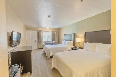a hotel room with two beds and a flat screen tv at The Oakhurst Inn at Yosemite in Oakhurst