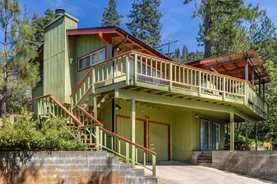 a green house with a balcony on top of it at Miglin Lakeview in Bass Lake