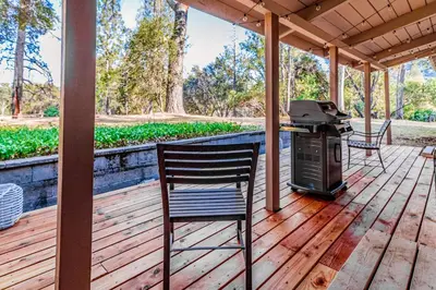 a patio with a grill and a chair on a deck at Pine Ridge Peak in Oakhurst