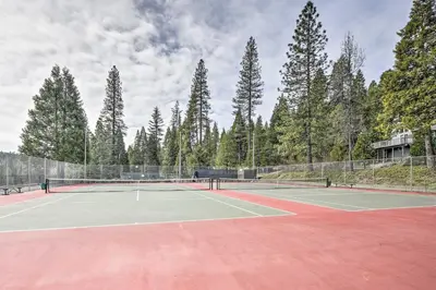 a tennis court with trees in the background at Game Room and Deck Oso Cozy Cabin in Arnold! in Arnold