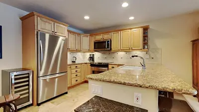 a kitchen with a stainless steel refrigerator and wooden cabinets at Spacious One Bedroom Condo in Mammoth! Free Assigned Parking - Snowbird 107 in Mammoth Lakes