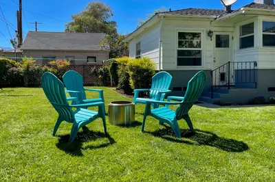 two blue chairs and a table in a yard at Vintage Bishop House in Downtown with Porch Swing! in Bishop