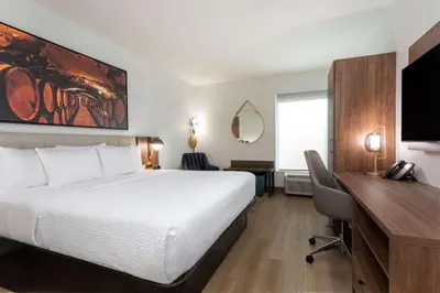 a hotel room with a bed and a desk with a computer at La Quinta Inn & Suites by Wyndham Galt Lodi North in Galt