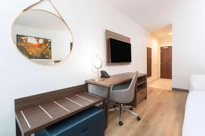 a hotel room with a desk and a mirror at La Quinta Inn & Suites by Wyndham Galt Lodi North in Galt