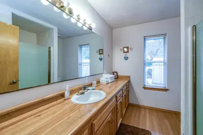 a bathroom with a sink and a large mirror at Black Bear Cabin in Bass Lake