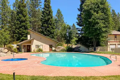 a swimming pool with a brick patio and a house at Willard Lake House in Bass Lake