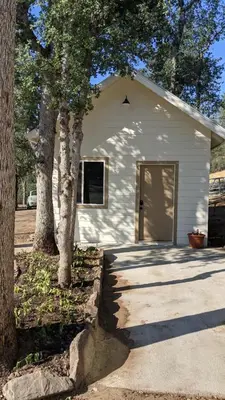 a white building with a door next to two trees at Clingan's Junction Cottage #4 in Squaw Valley