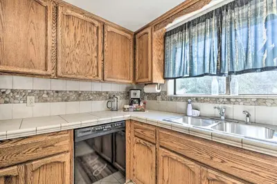 a kitchen with wooden cabinets and a sink and a window at Deck and Hot Tub Rustic Groveland Home! in Groveland