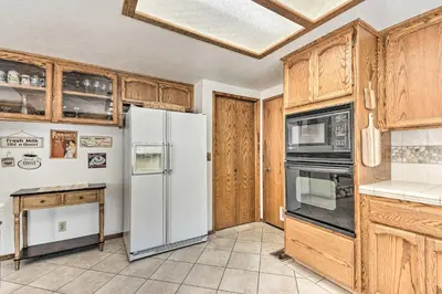 a kitchen with a white refrigerator and wooden cabinets at Deck and Hot Tub Rustic Groveland Home! in Groveland
