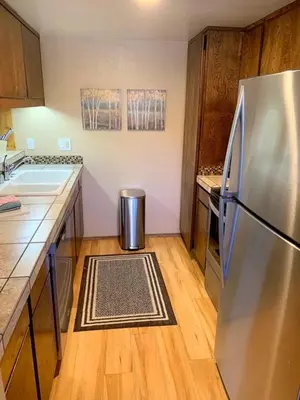 a kitchen with a stainless steel refrigerator and wooden floors at 1 Bedroom Standard Condos in Mammoth Lakes