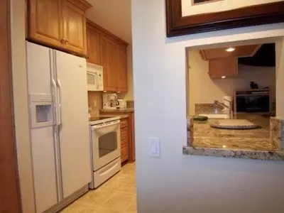 a kitchen with a white refrigerator and wooden cabinets at 1 Bedroom Premium Condos in Mammoth Lakes