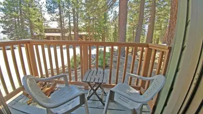 two chairs and a table on a deck with trees at Standard Condos with Free Parking in Mammoth Lakes