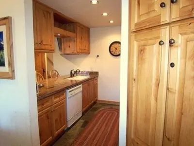 a kitchen with wooden cabinets and a clock on the wall at 2 Bedrooms Premium Condos in Mammoth Lakes