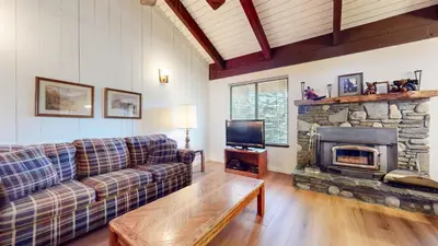 a living room with a couch and a stone fireplace at Discover 4 in Mammoth Lakes