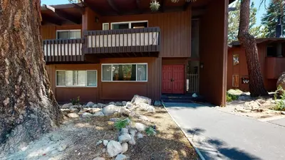 a house with a red door and a tree at Mammoth Estates Condo - Near Village at Mammoth & Pet Friendly in Mammoth Lakes