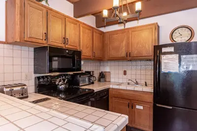 a kitchen with wooden cabinets and a black refrigerator at Val DIsere 32 Pet-Friendly, Walk To The Village, Private Washer Dryer, Spacious Floorplan condo in Mammoth Lakes