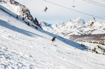 a person skiing down a snow covered slope with a ski lift at Val DIsere 32 Pet-Friendly, Walk To The Village, Private Washer Dryer, Spacious Floorplan condo in Mammoth Lakes