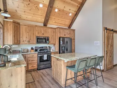 a kitchen with wooden cabinets and a counter with stools at Woodsy Retreat Modern Mi-Wuk Village Cabin! in Mi-Wuk Village