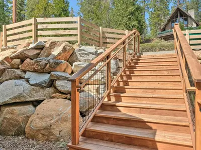 a wooden staircase next to a rock wall at Woodsy Retreat Modern Mi-Wuk Village Cabin! in Mi-Wuk Village