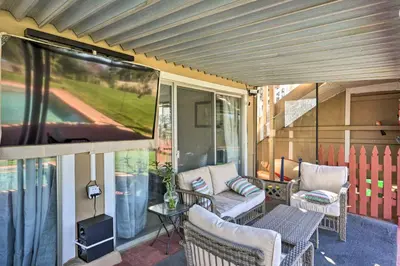 a screened in porch with a couch and chairs and a tv at Jackson Escape with Hot Tub and Mtn Views! in Jackson